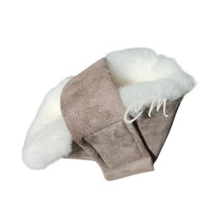 May include: A brown suede and white faux fur slipper with a folded-over cuff. The slipper is designed to be worn indoors.