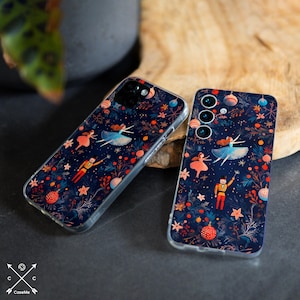 May include: Two phone cases with a dark blue background featuring a whimsical design of ballerinas, nutcrackers, and festive ornaments. The cases have a clear, protective border and a repeating pattern of stars and floral elements.