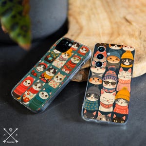 May include: Two phone cases with a colorful design featuring cats wearing hats and scarves. The cases are made of clear plastic and have a glossy finish.