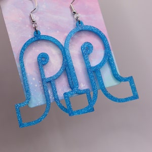 May include: A pair of blue glitter earrings with a unique geometric design. The earrings are made of a lightweight material and have a silver hook closure.