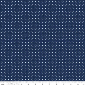 May include: Navy blue fabric with a repeating pattern of small white polka dots. The fabric is marked with inch measurements along the bottom edge, and the text "Riley Blake Designs" is visible.