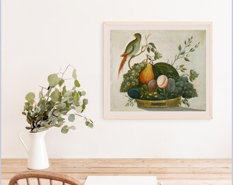 Op de afbeelding: Een ingelijst stilleven schilderij met een mand vol druiven, peren en pruimen. Een kleurrijke vogel zit op een tak boven het fruit. Het kunstwerk wordt aan een muur boven een houten tafel getoond.