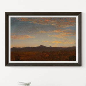Puede incluir: Impresión artística enmarcada que representa una puesta de sol sobre un terreno montañoso. El cielo es una gradación de azul y naranja, con nubes iluminadas por el sol poniente. La obra de arte está enmarcada en un marco marrón oscuro.