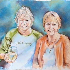 K&ouml;nnte beinhalten: Ein Aquarellgem&auml;lde von zwei l&auml;chelnden Personen. Die Person links tr&auml;gt ein wei&szlig;-olivgr&uuml;nes Raglan-Shirt mit dem Text Life is good und h&auml;lt ein Weinglas. Die Person rechts tr&auml;gt eine orangefarbene Strickjacke &uuml;ber einem wei&szlig;en Oberteil.