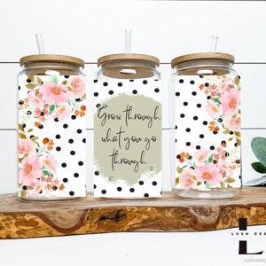 Puede incluir: Tres vasos de vidrio transparente con tapas de bambú y pajitas. Cada vaso tiene un diseño diferente. Uno tiene un patrón floral con lunares negros, otro tiene lunares negros con el texto "Grow through what you go through", y el tercero tiene un patrón floral con lunares negros.