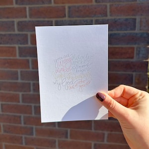 Könnte beinhalten: Eine weiße Karte mit einer handgeschriebenen Botschaft in rosa, gelber und blauer Tinte. Die Botschaft lautet: "Du bist der Weg, das Wunder, der Schöpfer, der Arbeiter, der Hüter des Versprechens, das Licht in der Dunkelheit, mein Gott, der sagt, dass du bist."