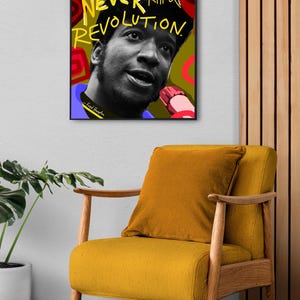 Puede incluir: Un cuadro enmarcado con un retrato en blanco y negro y el texto "You can kill a revolutionary, but you can NEVER kill a REVOLUTION." El cuadro est&aacute; sobre una silla amarilla con un coj&iacute;n a juego.
