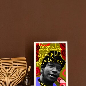 Puede incluir: Una impresi&oacute;n art&iacute;stica enmarcada con un retrato en blanco y negro de Fred Hampton y el texto "You can kill a revolutionary, but you can NEVER kill a REVOLUTION". La obra de arte utiliza los colores rojo, verde y amarillo.