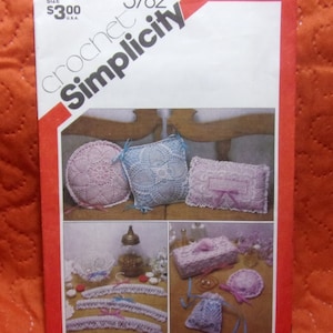 May include: Crochet pattern Simplicity 5782 for crocheting a variety of home decor items, including pillows, a tissue box cover, a jewelry bag, and a hanger. The pattern includes instructions for crocheting in pink, blue, and white.