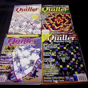 May include: A stack of four The Quilter magazines featuring various quilting designs and projects. The covers showcase colorful quilts with floral patterns, geometric shapes, and traditional designs. The magazines are titled "The Quilter" and feature articles on quilting techniques, patterns, and inspiration.