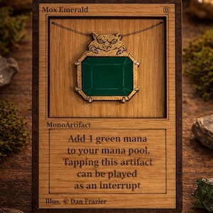 May include: Wooden Mox Emerald card featuring a green gem pendant with gold accents. The card includes text: "Add 1 green mana to your mana pool. Tapping this artifact can be played as an interrupt." Illustration by Dan Frazier.