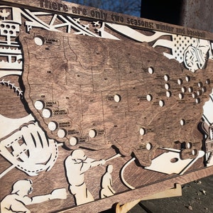 May include: A wooden map of the United States with the location of all Major League Baseball stadiums marked. The map is decorated with baseball-themed imagery, including a baseball glove, a bat, and a baseball. The text "There are only two seasons: winter and baseball" is printed at the top of the map.