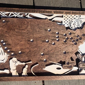 May include: A wooden map of the United States with a baseball theme. The map shows the location of all Major League Baseball stadiums. The text "There are only two seasons: winter and baseball" is at the top of the map. The text "Play Ball!" is at the bottom of the map.