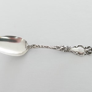 Puede incluir: Una cuchara de plata con un mango adornado y una inscripción con monograma. La cuchara tiene un diseño clásico y está en excelente estado.