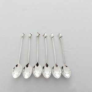 Może przedstawiać: Zestaw sześciu srebrnych łyżeczek do herbaty z uchwytami w kształcie gruszki.