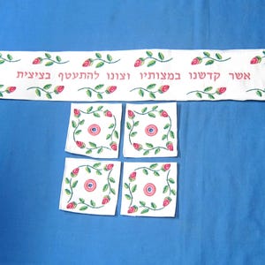 May include: White fabric with embroidered pink roses and green leaves. The fabric has the Hebrew text "Asher Kibartinu Ve'anuni Le'harisheni Be'aliya" embroidered on it. There are four smaller squares of fabric with the same design.