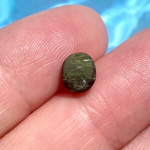May include: A dark green oval-shaped gemstone with a shimmery, iridescent finish.