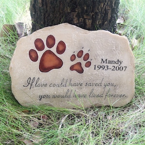 May include: A light brown stone memorial with two paw prints, one larger than the other. The stone has the text "Mandy 1993-2007" and the inscription "If love could have saved you, you would have lived forever."