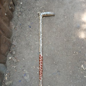 Peut inclure: Une canne en bois avec un motif zèbre noir et blanc et un motif girafe brun sur la partie inférieure.