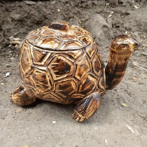 May include: A wooden turtle shaped box with a hinged lid. The turtle is brown and black with a detailed shell.