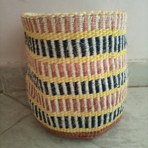 May include: A woven storage basket with a striped pattern in black, white, yellow, and brown.