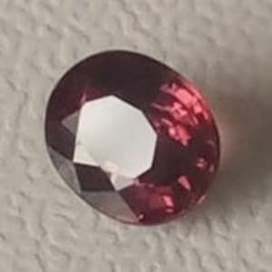 Op de afbeelding: Een dieprode ovale edelsteen met een facetgeslepen vorm.