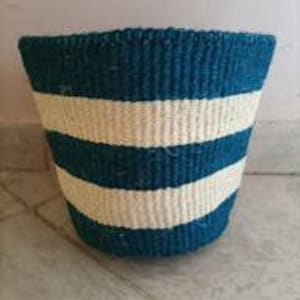 Könnte beinhalten: Ein geflochtener Korb aus Naturfasern in Teal und Weiß mit Streifen. Der Korb ist zylindrisch geformt und hat eine breite Öffnung.