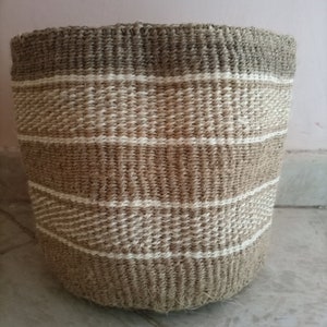May include: A woven basket with a natural brown and white striped pattern. The basket is made of natural fibers and has a cylindrical shape.