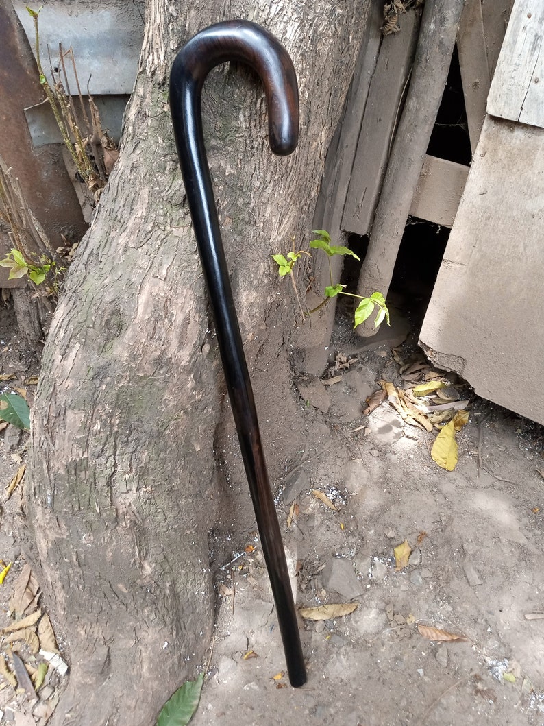 May include: A black wooden walking stick with a curved handle.