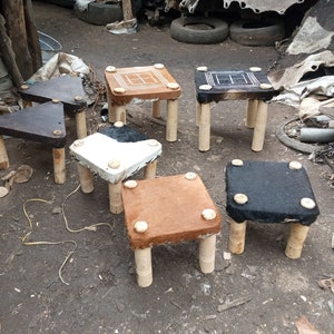 May include: Six small wooden stools with different colored and patterned upholstery. The stools are made of wood and have four legs. The upholstery is made of leather and has a variety of patterns, including black and white, brown, and black.