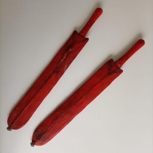 May include: Two red wooden swords with a textured surface. The swords are about 30 inches long.