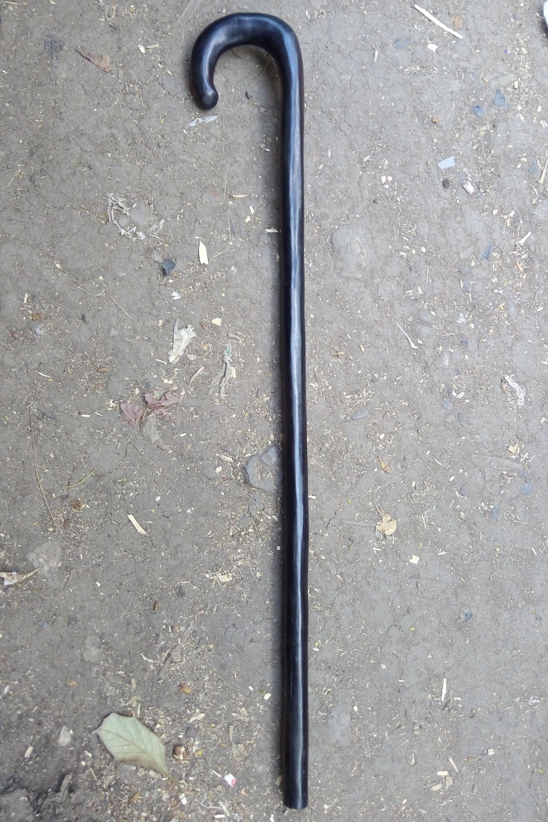 May include: A black wooden walking stick with a curved handle.