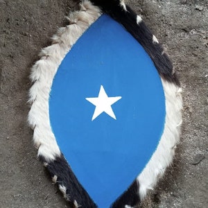 May include: A blue shield with a white five-pointed star in the centre. The shield is made of leather and has a white and black fur trim.