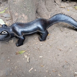 May include: A black wooden crocodile sculpture with a long tail. The crocodile has a detailed mouth and eyes.