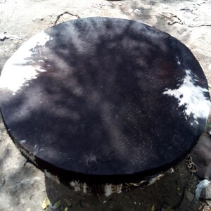 Puede incluir: Un tambor redondo negro y blanco con una cabeza de cuero. El tambor est&aacute; hecho de madera y tiene una franja alrededor del borde.