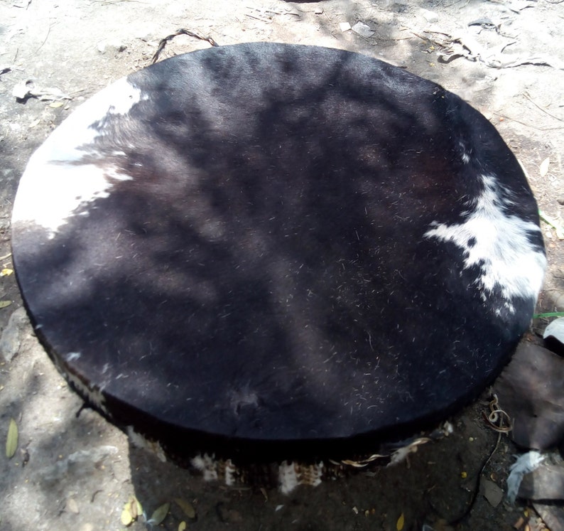 Puede incluir: Un tambor redondo negro y blanco con una cabeza de cuero. El tambor est&aacute; hecho de madera y tiene una franja alrededor del borde.
