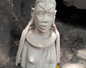 Puede incluir: Una escultura de madera blanca de un busto de persona con detalles intrincados en la cabeza y el pecho. La escultura está tallada en un estilo tradicional africano.