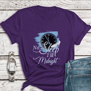 Può includere: Maglietta viola con un grafico di orologio e scarpetta di vetro blu e bianco. Il testo sulla maglietta recita "No Sleep Till Midnight".