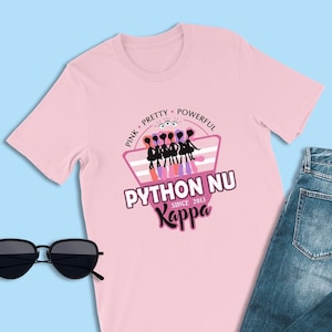 Peut inclure: T-shirt rose avec un motif graphique représentant un groupe de femmes en silhouette avec le texte "Pink Pretty Powerful Python Nu Kappa Since 2013".