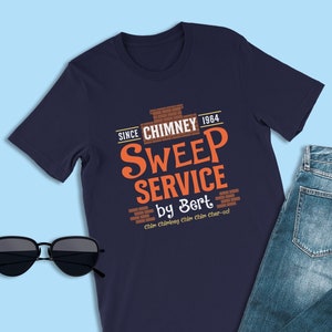 May include: A navy blue t-shirt with a vintage-style graphic design featuring a brick chimney and the text "Since Chimney 1964 Sweep Service by Bert Chân Chương Chân Chim Cher-odd".