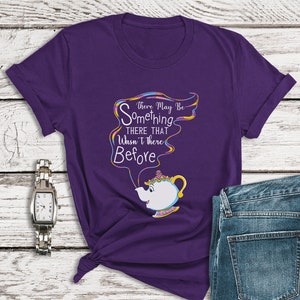 Puede incluir: Camiseta morada con un gráfico colorido de una tetera con cara y el texto "There May Be Something There That Wasn't There Before".