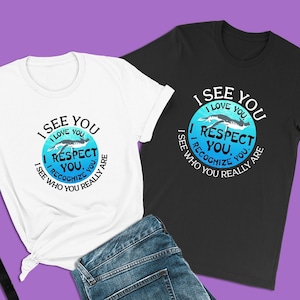 May include: Two t-shirts with a graphic design of a blue circle with the text "I See You, I Love You, I Respect You, I Recognize You, I See Who You Really Are" in white text. The t-shirts are white and black.