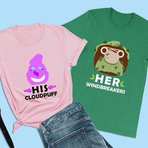 以下が含まれることがあります： デザインが一致した2枚のTシャツ。ピンクのTシャツには、紫色の漫画キャラクターと「His Cloudpuff」の文字が書かれています。緑のTシャツには、緑色のセーターを着た漫画のサルと「Her Windbreakers」の文字が書かれています。
