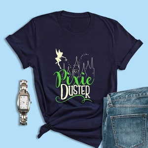 May include: A navy blue t-shirt with a green and white graphic of Tinkerbell flying over a castle with the text "Pixie Duster".