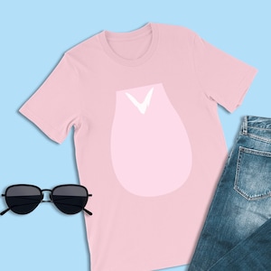 Pu&ograve; includere: Una maglietta rosa con una grafica bianca di un bocciolo di fiore stilizzato. La maglietta &egrave; abbinata a jeans blu e occhiali da sole neri.