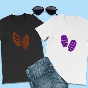 Puede incluir: Dos camisetas con un diseño de huella. Una camiseta es negra con huellas marrones que dicen "ANDY" y la otra camiseta es blanca con huellas moradas que dicen "WOODY".