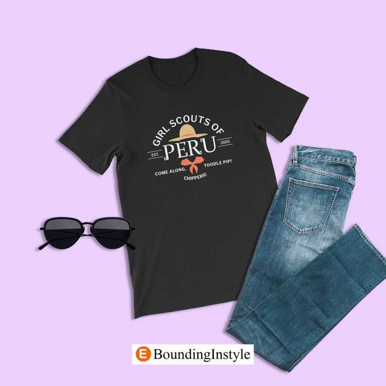 May include: Black t-shirt with a white graphic of a girl scout patch. The patch features a straw hat with a red bow and the text "Girl Scouts of Peru Est. 2005 Come Along. Toodle Pip! Chippers!"