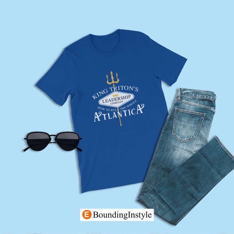 May include: A royal blue t-shirt with a gold graphic of a trident and a sign that reads "King Triton's Leadership Company How to Rule the Whole Atlantica".