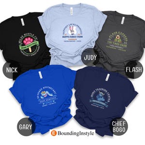 May include: Five t-shirts in various colors, each featuring a unique graphic design. The designs include text and illustrations related to a cartoon theme. The shirts are labeled with character names: Nick, Judy, Flash, Gary, and Chief Bogo.