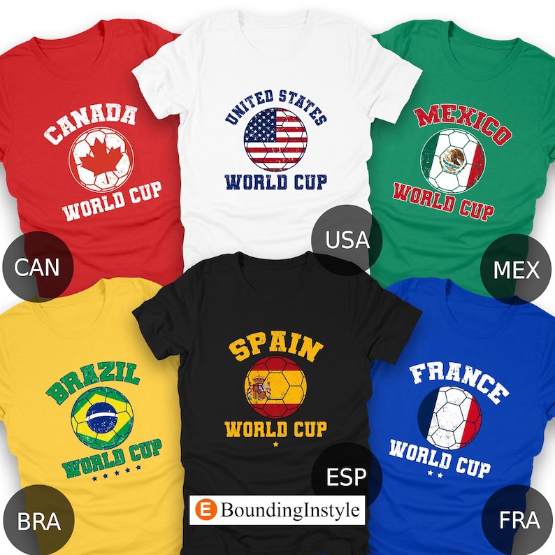 May include: A collection of t-shirts in various colors, each featuring a soccer ball design with the text "WORLD CUP" and the names of different countries: Canada, United States, Mexico, Brazil, Spain, and France.